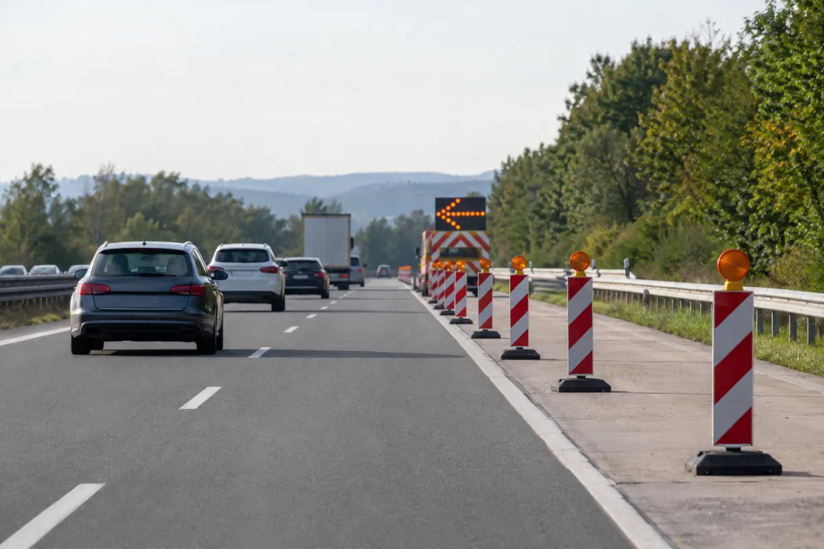 Autostrada z wygrodzonym prawym pasem i pojazdem służb drogowych w oddali