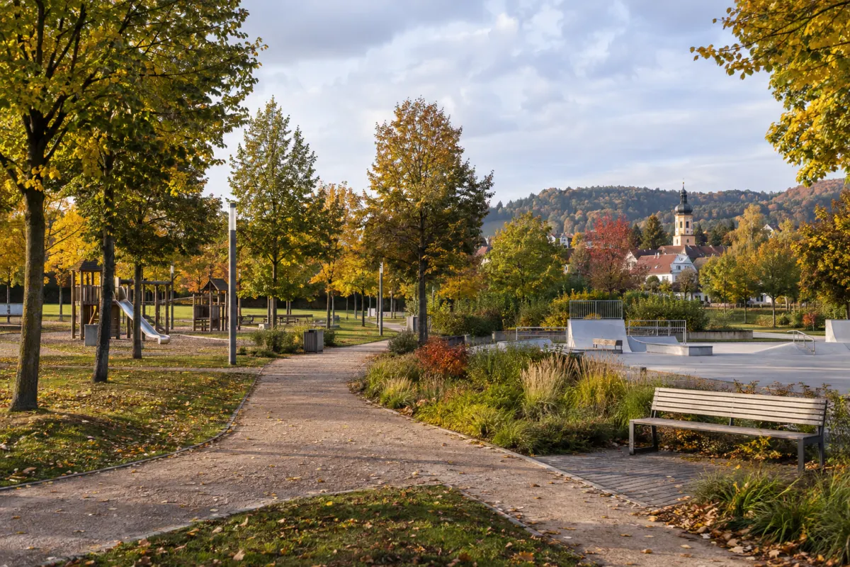 Zielony park w niemieckim mieście, alejki, plac zabaw i skatepark bez ludzi